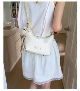 Detail of cream croissant bag with yellow straps and cute sheep plush charm decoration