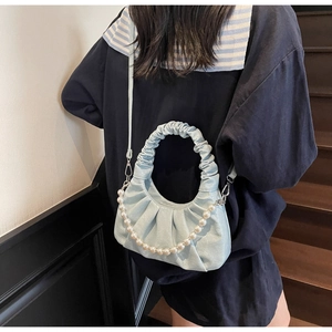 Detail of light blue pleated cloud bag with pearl chain shown as crossbody on a model