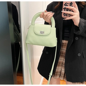 Detail of mint green quilted bag with vertical ripple texture and silver turn-lock closure