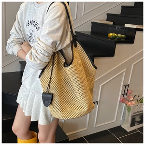 Détail du sac cabas en paille minimaliste avec bordures et bandoulières en cuir noir