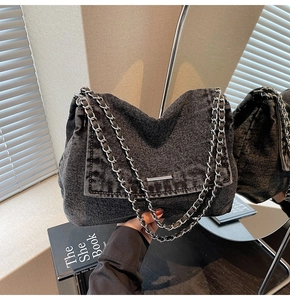 Detailed close-up of washed black denim shoulder bag with bold silver metal chain strap