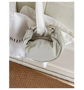 Détail du mini sac dumpling en nylon vert clair avec crochet sur un sac en toile