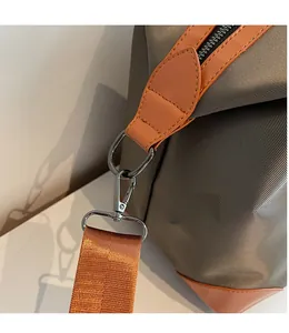 Macro shot of gray canvas travel bag featuring durable metal swivel hooks and orange trim