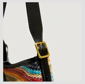 Détail de la bandoulière en cuir noir réglable avec boucle dorée sur un sac tissé