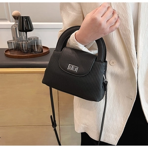 Detailed close-up of a black textured crossbody bag with silver twist lock and leather strap