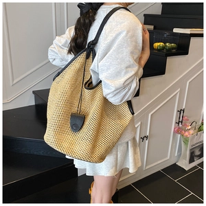 Gros plan sur le sac fourre-tout en paille tissée avec bandoulière noire en cuir