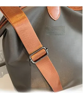 Detail of olive nylon boston bag with bright orange strap and brown leather trim