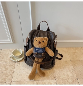 Detail of vintage brown printed backpack featuring a cute teddy bear plush accessory
