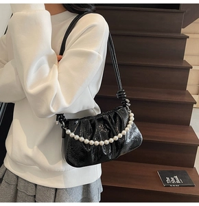Dettaglio borsa a mano in pelle stropicciata nera con elegante catena di perle sulla tracolla