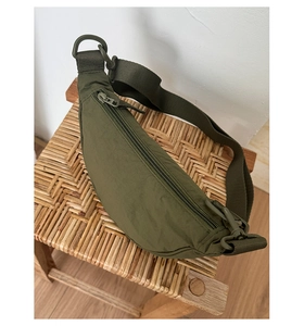 Détail du sac demi-lune en nylon vert armée avec bandoulière large et boucle en plastique