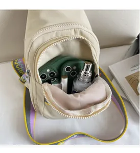 Vue détaillée du sac bandoulière beige ouvert montrant le rangement interne et la sangle