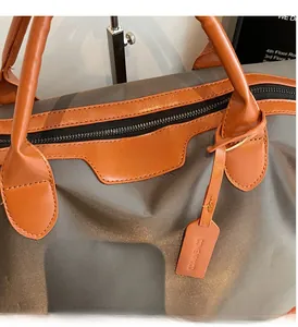 Close-up of smooth metal zipper and reinforced leather handle on grey travel duffel bag
