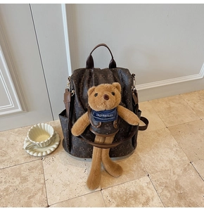 Detailed close-up of dark brown backpack with bear print and cute plush bear accessory