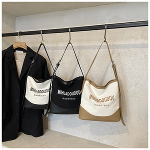 Close-up of contrast canvas tote bags with leather trim and shoulder straps on hangers