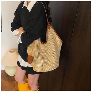 Vue latérale du grand sac cabas tissé beige avec anses en cuir marron et pendentif