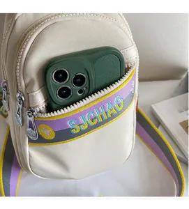 Vue détaillée du sac bandoulière compact montrant les zips et l'espace pour téléphone