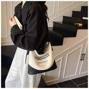 Detailed shot of large black and white canvas tote bag with leather base and letter print