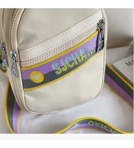 Détails des sangles rayées colorées et des fermetures éclair argentées d'un sac à bandoulière beige