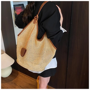 Détail d'un grand sac cabas en paille avec bandoulière en cuir porté par un mannequin femme