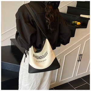 Detail of black and white canvas tote bag showing the texture and leather stitching details