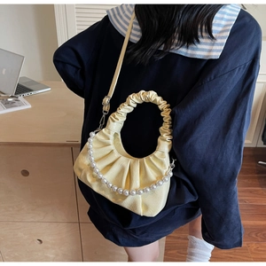 Vista dettagliata di una borsa a nuvola gialla con catena di perle su un modello