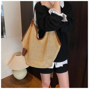 Détail d'un grand sac cabas tissé beige avec bordure en cuir marron porté par un mannequin