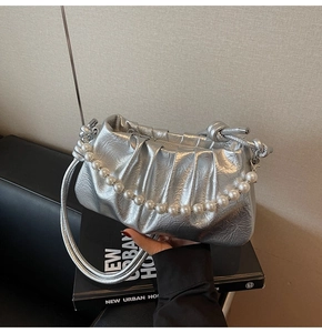 Dettaglio borsa a nuvola argento con catena di perle e texture metallica a pieghe