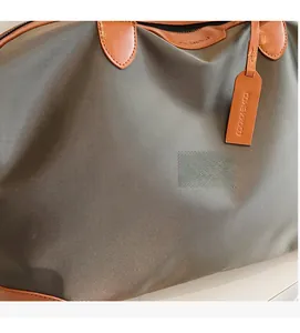 Close-up of charcoal grey nylon fabric with premium brown leather strap and hangtag