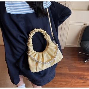 Dettaglio della borsa a mano gialla a pieghe con perle decorative e tracolla regolabile
