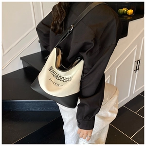 Detail view of contrast canvas tote bag featuring black leather trim and printed logo