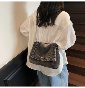 Detailed shot of dark grey denim tote with silver chain strap and white stitching