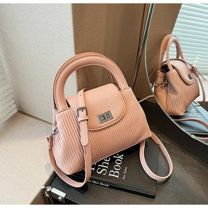 Detail of pink quilted handbag showing vertical pleated texture and metal swivel lock