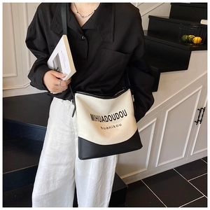 Detail of minimalist black and white canvas bucket bag with adjustable shoulder strap