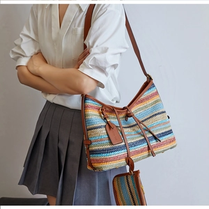 Détail du sac cabas tissé à rayures colorées avec anses en cuir marron et porte-monnaie