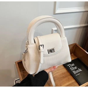 Close-up of elegant cream quilted chain crossbody bag with pleated texture and metal clasp