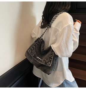 Detail of distressed grey denim tote bag with silver chain strap and metal flap buckle