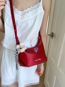 Elegant burgundy leather shoulder bag with a cute puppy plush charm and silver nameplate