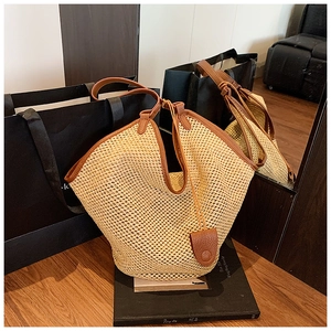 Gros plan du sac fourre-tout en paille avec garniture et poignées en cuir marron grainé