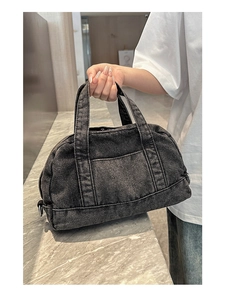 Detail of black washed denim boston bag showing textured fabric and sturdy top handles