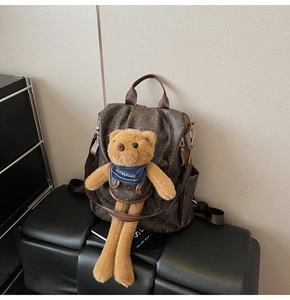 Detail of printed brown backpack with cute long-legged teddy bear plush charm