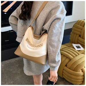Detail of canvas and leather tote with brown lettering and sturdy crossbody shoulder strap