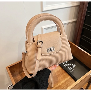 Detail of beige quilted mini bag featuring vertical texture and silver metal twist lock