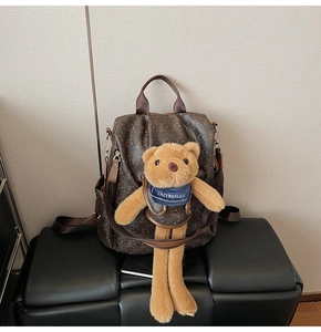 Detail of printed brown backpack with bear pattern and matching plush toy charm