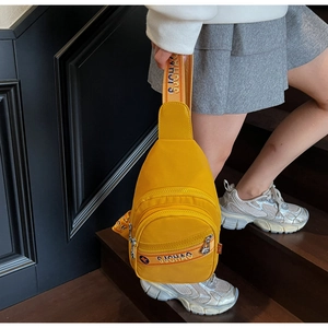 Détail du sac bandoulière jaune vif montrant plusieurs fermetures éclair et nylon durable