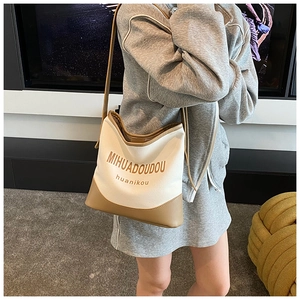 Close-up of contrast canvas tote bag worn by a model in a minimalist indoor setting