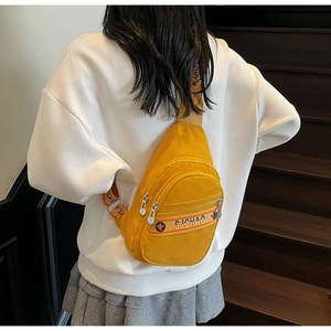 Détail du sac bandoulière jaune en nylon avec poches zippées et sangles tissées colorées