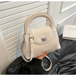Detail of beige quilted mini bag featuring vertical patterns and silver twist lock closure