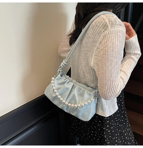 Dettaglio della borsa a nuvola plissettata azzurra con elegante tracolla di perle