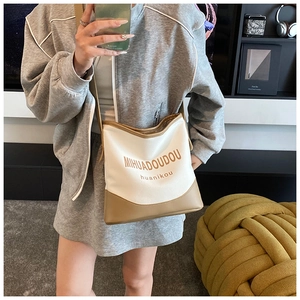 Detail of canvas and leather crossbody bucket bag shown in a mirror selfie for size scale