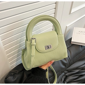 Detail of light green pleated leather handbag with metallic turn-lock and round handle